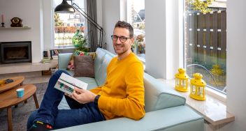 Sander Holterman van de Verzekerdenraad leest een boek in zijn woonkamer